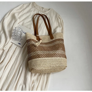 Détail du motif tressé et du gland en perles de bois sur le sac de plage en paille