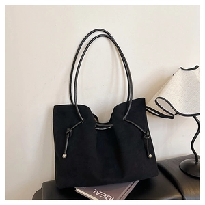 Close-up of black suede tote bag with drawstring leather straps and metal accents
