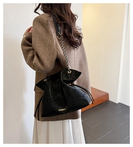 Detail of black frosted shoulder bag with gold Fashion lettering and chain strap