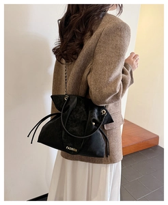 Detail of black drawstring chain bag with gold FASHION logo and frosted texture