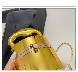 Macro detail of glossy gold cylinder clutch showing metallic finish and mechanical lock
