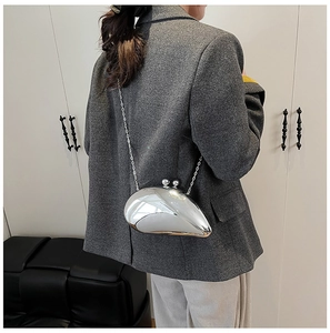 Irregular silver pod-shaped acrylic evening clutch bag worn with metal chain strap
