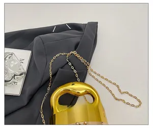 Detail shot of a glossy gold acrylic evening clutch with a sleek metallic handle