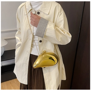 Irregular gold metal clutch bag with mirror finish and slim chain strap worn by model
