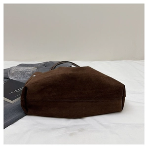 Detailed close-up showing the wide bottom and suede texture of a large brown tote bag