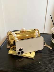 Détails d'un sac de soirée doré effet miroir avec poignée et fermoir en perles chic