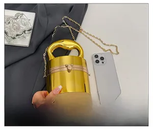 Miniature gold cylinder bag with metallic mirror finish compared to a smartphone