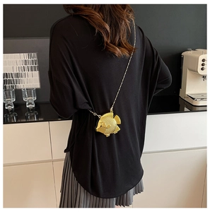 Dettaglio di una borsa da sera a forma di pesce dorato con trama a scaglie e catena sottile