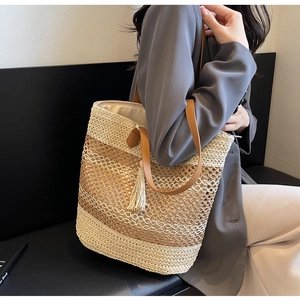 Détail du sac cabas en paille tissée à carreaux avec lanières en cuir et pompon bohème