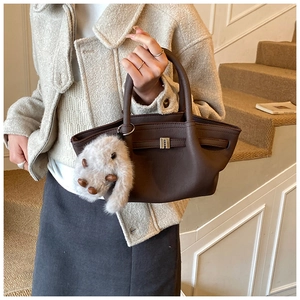 Detail of dark brown pebble leather bucket bag with plush rabbit charm and metal clasp