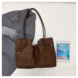 Detail of dark brown faux suede tote bag featuring drawstring tassels and shoulder strap