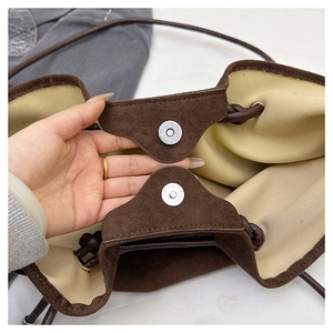 Detail of magnetic silver buckles and beige lining on vintage faux suede shoulder bag