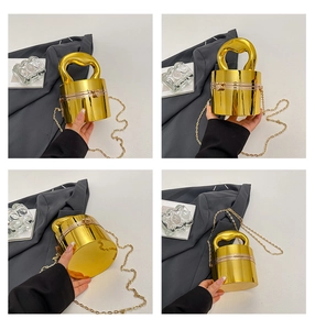 Vue détaillée du sac seau cylindrique doré avec poignée ondulée en métal poli
