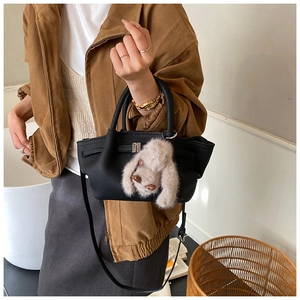 Detail of black leather bucket bag with gold hardware and plush rabbit charm