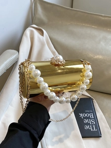 Détail de la pochette dorée miroir avec grande poignée en perles et fermoir perle