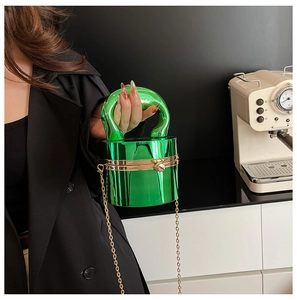 Détail du sac cylindrique en acrylique vert métallisé avec accessoires dorés