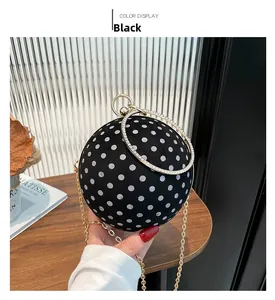 Detail of spherical black polka dot evening bag with rhinestone handle and gold chain