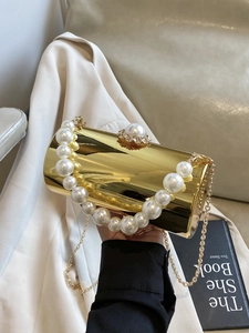 Détail de la pochette de soirée cylindrique dorée avec anse perle et fermoir strass