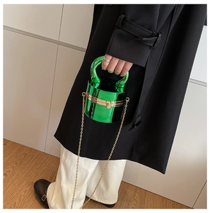 Détail du sac rond en acrylique vert métallisé brillant avec chaîne et poignée dorées