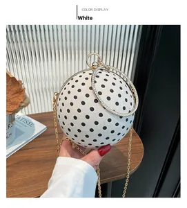 Close-up of a spherical polka dot handbag with rhinestone ring handle and golden chain