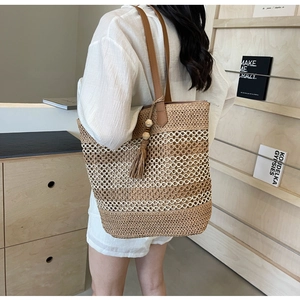 Détail du sac cabas en paille tressée avec lanières en cuir et pompons décoratifs