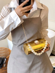 Détail du sac de soirée cylindre doré avec poignée en perles et chaîne métal