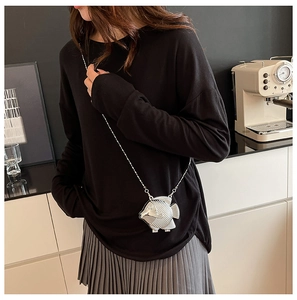 Dettaglio della pochette a forma di pesce argento con squame e tracolla a catena