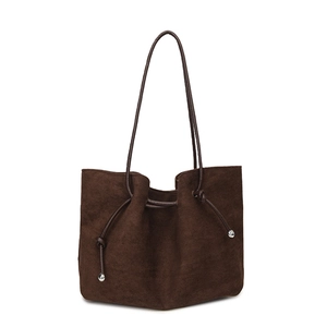 Detailed view of dark brown suede shoulder bag with drawstring design and metal ball buckle