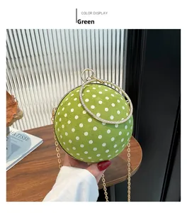Close-up of a green suede sphere handbag with white dots and gold rhinestone handle