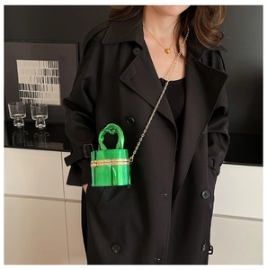 Detail showing the glossy green bucket bag with a knotted top handle and gold chain