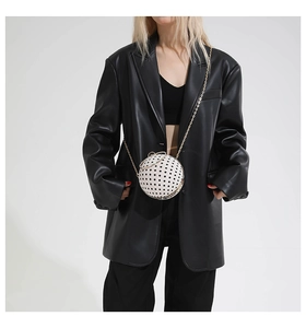 Spherical chain bag with polka dots shown on a model wearing a black leather suit