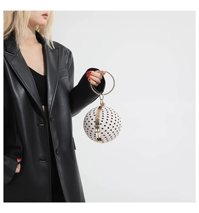 Close-up of a polka dot sphere evening bag with a metallic ring handle on a model