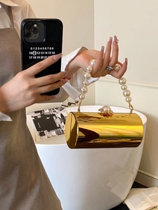 Gros plan détaillé d'un sac de soirée cylindrique doré doté d'une poignée en perles
