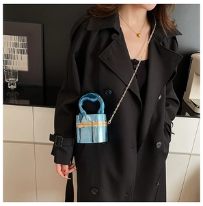 Electric blue cylindrical acrylic bag held by a model in a black trench coat