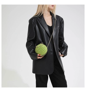 Close-up of green polka dot spherical bag with gold chain and metal ring handle detail