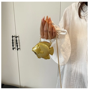 Dettaglio borsa da sera a forma di pesce con scaglie dorate e tracolla a catena metallica