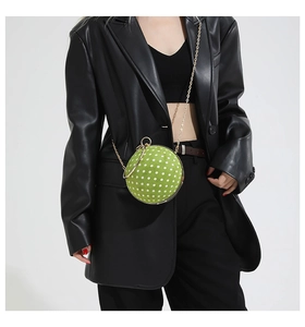 Close-up of green polka dot spherical bag with gold chain and round metal handle
