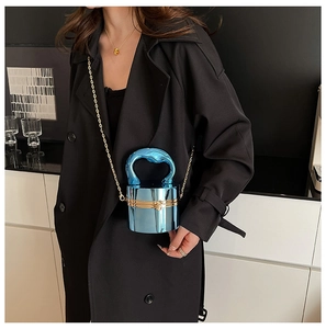 Détail du sac seau bleu métallisé avec une poignée élégante et fine chaîne dorée
