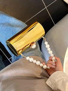 Détail d'un sac de soirée cylindrique doré avec effet miroir et anse en perles