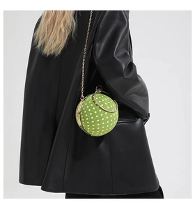 Detail of green polka dot spherical bag with metal chain and crystal handle on a model