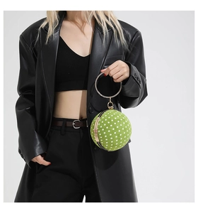 Close-up of bright green polka dot spherical bag with a rhinestone gold ring handle