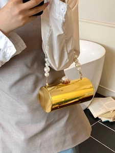 Détail du sac de soirée cylindrique doré avec anse en perles et fermoir en strass