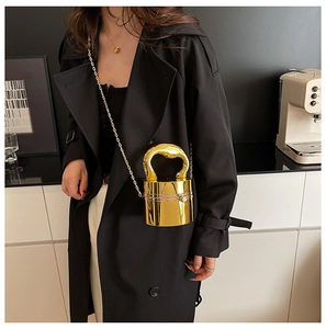 Detail of a cylindrical gold mirror bag featuring a sturdy curved metal handle and chain