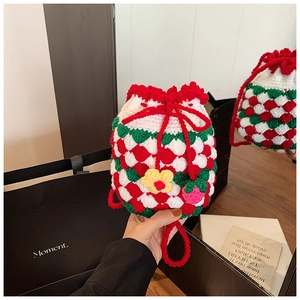 Detail of handmade crochet strawberry bucket bag with knit floral and fruit charms