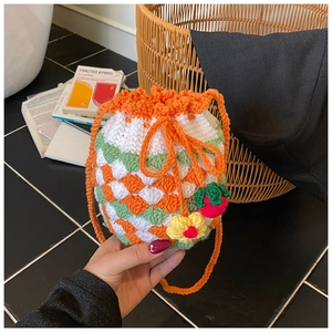 Close-up of handmade crochet bucket bag featuring colorful knit textures and strawberry charms