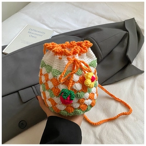 Detail of handmade crochet strawberry bucket bag with knit texture and orange strap