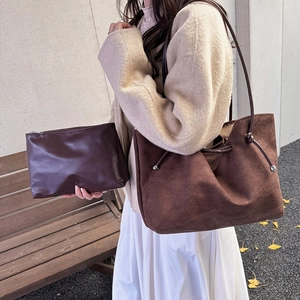 Vintage brown suede shoulder bag with interior clutch shown in a scenic outdoor setting