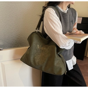Close-up of dark green tote bag featuring daisy embroidery and Maodi branding details