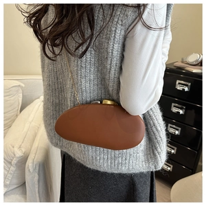 Detailed view of brown pebble-shaped clutch bag with gold chain and dual-tone clasp
