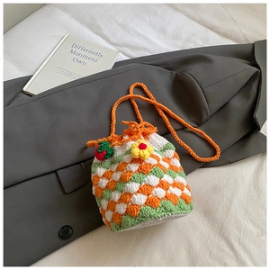 Detail of handmade crochet bucket bag featuring woven textures and strawberry charm